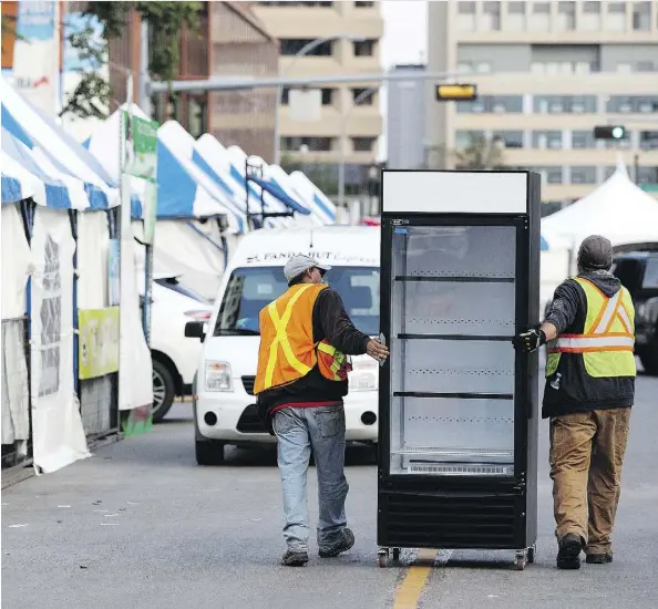  ?? DAVID BLOOM ?? Workers push a cooler down 99 Street on Tuesday as they set up for the 33rd annual Taste of Edmonton festival, which starts Thursday.