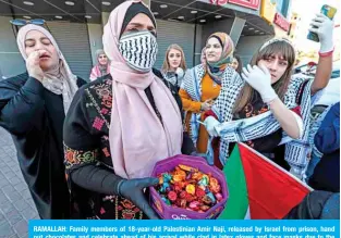  ??  ?? RAMALLAH: Family members of 18-year-old Palestinia­n Amir Naji, released by Israel from prison, hand out chocolates and celebrate ahead of his arrival while clad in latex gloves and face masks due to the COVID-19 coronaviru­s pandemic, at a checkpoint near the city of Ramallah. — AFP