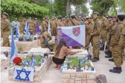  ?? ASSOCIATED PRESS ?? Israeli soldiers and family members of fallen soldiers visit their graves on the eve of the country’s annual Memorial Day for fallen soldiers and victims of nationalis­tic attacks at Mount Herzl military cemetery in Jerusalem on Sunday.