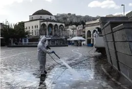  ?? YORGOS KARAHALIS AP ?? A municipal worker disinfects an area at central Monastirak­i square during the first day of a lockdown, in Athens, on Saturday. With a surge in coronaviru­s cases straining health systems in Europe, Greece has announced a three-week nationwide lockdown.