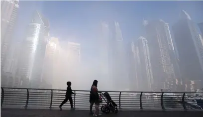  ??  ?? Water, land, sky, sun and fog meet at this spot on the Dubai Marina to render an almost ethereal visual effect, as residents take a stroll.