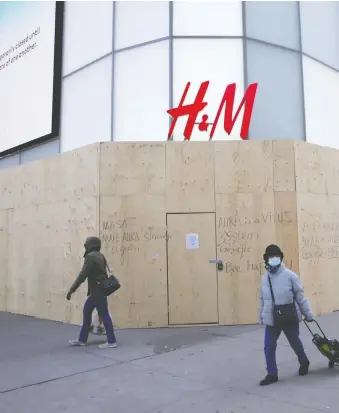  ?? CHRIS HELGREN/REUTERS ?? Pedestrian­s pass a boarded-up H&M clothing store in Toronto last month. Commercial real estate experts say companies are rethinking their real estate footprints in the aftermath of COVID-19.