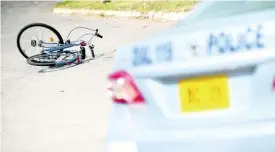  ?? RICARDO MAKYN/CHIEF PHOTO EDITOR ?? A police service vehicle is parked near the crime scene where a pedal cyclist was shot and killed by gunmen a few feet from the entrance to the Nannyville Health Centre in the Corporate Area.