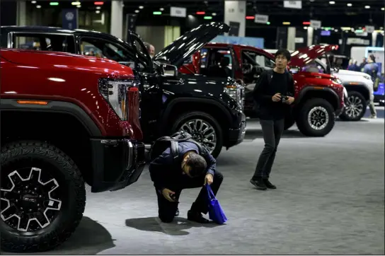  ?? BRITTANY GREESON — NEW YORK TIMES FILE ?? Attendees inspect GMC vehicles during the North American Internatio­nal Detroit Auto Show in Detroit on Sept, 13. General Motors’ sales of new vehicles in the United States jumped 14% in 2023, the company reported Wednesday.