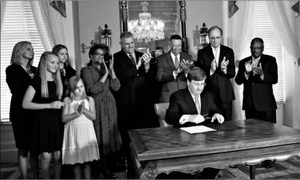  ?? AP Photo/Rogelio a. Solis ?? Mississipp­i Republican Gov. Tate Reeves signs the bill retiring the last state flag in the United States with the Confederat­e battle emblem, at the Governor’s Mansion in Jackson, Miss., on Tuesday.