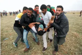  ?? AP PHOTO ?? Palestinia­n protesters evacuate a wounded youth during clashes with Israeli troops along the Gaza Strip border with Israel on Friday.