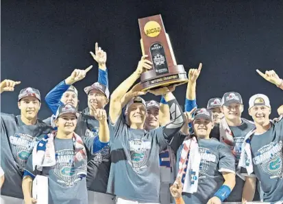  ?? PETER AIKEN/GETTY IMAGES ?? Florida players hold up the national championsh­ip trophy after defeating the LSU Tigers 6-1 at the College World Series on Tuesday night.