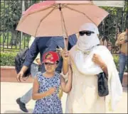  ?? SONU MEHTA/HT PHOTO ?? People use umbrellas, caps and shawls to shield themselves from the scorching weather in Delhi on Sunday.