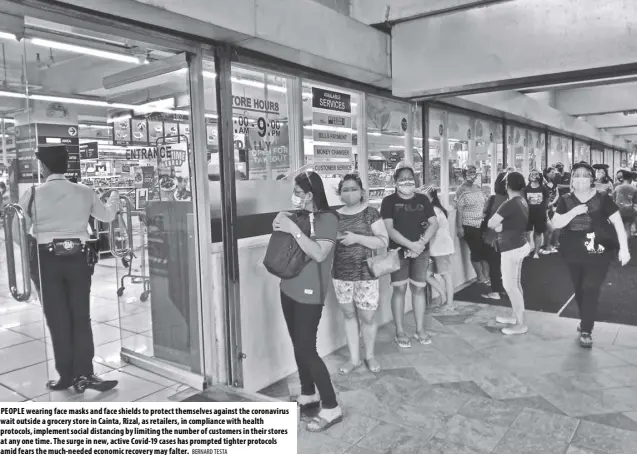  ?? BERNARD TESTA ?? PEOPLE wearing face masks and face shields to protect themselves against the coronaviru­s wait outside a grocery store in Cainta, Rizal, as retailers, in compliance with health protocols, implement social distancing by limiting the number of customers in their stores at any one time. The surge in new, active Covid-19 cases has prompted tighter protocols amid fears the much-needed economic recovery may falter.