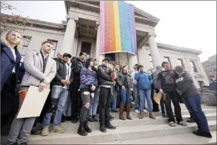  ?? AP photo ?? Supporters of Club Q stand beneath a 25-foot historic pride flag displayed on the exterior of city hall to mark the weekend mass shooting at a gay nightclub on Wednesday, in Colorado Springs, Colo.