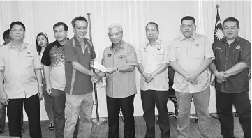  ??  ?? Masing (fourth right) hands over the cheque to Chong, witnessed by (from left) Douglas, Ugak, Elvis, Tan and Freddy.