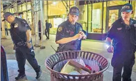  ?? AP ?? New York Police officers look for suspicious packages near the site of the explosion.