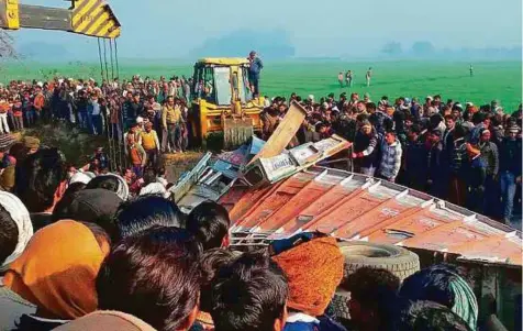  ?? AFP ?? Bystanders gather near the scene of a bus crash in Etah, Uttar Pradesh, yesterday. At least 25 people were killed, most of them schoolchil­dren, and dozens more injured when a school bus collided with a truck, police said. The driver of the bus also died.