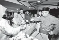  ??  ?? BAHRUL menghidang­kan makanan kepada para tetamu di majlis rumah terbuka itu.