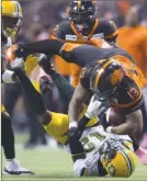 ?? The Canadian Press ?? B.C. Lions running back Tyrell Sutton (13) topples over Edmonton Eskimos defensive back Forrest Hightower (12) during CFL action in Vancouver on Friday night. The Lions won 42-32.