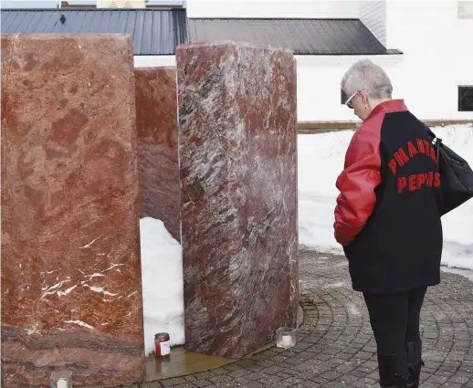  ??  ?? Stacy Hickey-Buraglia se recueille devant un monument construit à la mémoire des Boys in Red vendredi matin à Bathurst. - Acadie Nouvelle: David Caron