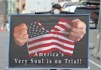  ?? PHOTOS BY TREVOR HUGHES/USA TODAY ?? A man carries a sign in Minneapoli­s during the trial of former Officer Derek Chauvin.