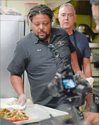  ??  ?? Above left, Rod Cornish moves a tray of tomatoes as he films an episode of “Winging It,” featuring local attorney Scott Sawyer, right, at Cornish’s restaurant, Hot Rod Cafe, in New London last month.
Right, Sawyer adds garlic and basil to what will be a roasted tomato sauce. “Winging It” is featured on a youTube channel Cornish and his head chef Carlos Paucar started after the COVID-19
pandemic began.