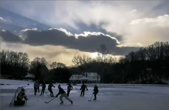  ?? Steph Chambers/Post-Gazette ?? Friends play hockey in single-digit temperatur­es at dusk Friday on Keith and Sally Turnbull’s pond along Fairview Road in Fox Chapel. The Turnbulls, who built their house in the 1970s, have allowed neighborho­od kids to use their pond for decades. “The...