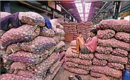  ??  ?? A labourer rests on the onion sacks at Azadpur Mandi