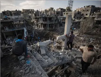  ??  ?? Palestinia­ns among ruins of their homes after airstrikes in the town of Beit Hanoun, northern Gaza Strip