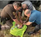  ?? OAKLAND COUNTY SHERIFF’S OFFICE ?? A deputy and other first responders stabilize the infant at the scene where he was found abandoned Wednesday.