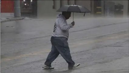  ?? AP PHOTO/JEFF CHIU ?? A man carries an umbrella as he crosses the street in San Francisco, on Wednesday.