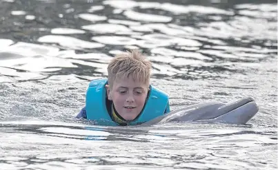  ?? Picture: PA. ?? Nathan Korol, from Dundee, swims with a dolphin at Discovery Cove in Orlando during the Dreamfligh­t holiday to Florida.