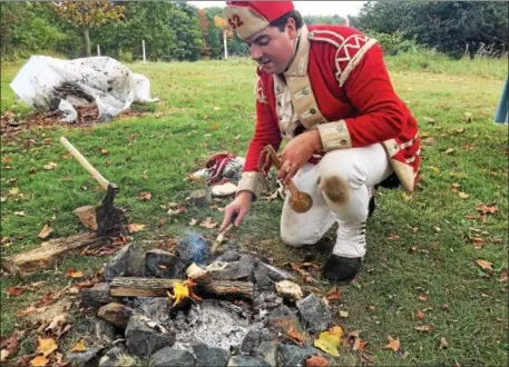  ??  ?? An historical re-enactor potraying a soldier in the 62nd British Regiment stokes a campfire at Saratoga National Historical Park on Saturday. (Paul Post photo)