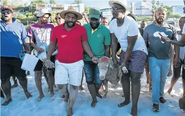  ??  ?? Protest leader Chumani Maxwele (red T-shirt) prepares to slaughter a sheep on Clifton’s Fourth Beach on Friday in a supposed ritual to tackle racism after beachgoers were told to leave the beach on December 23 by guards of private security firm PPA.