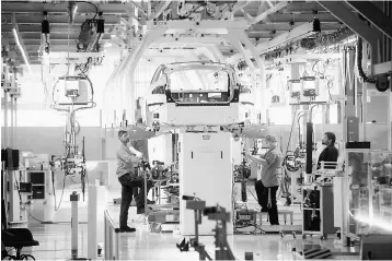  ??  ?? Tesla workers examine a Model S used for training and tool calibratio­n at the company’s factory in Fremont, California. Quality checks have routinely revealed defects in more than 90 per cent of Model S and Model X vehicles inspected after assembly,...