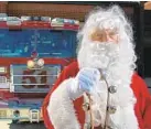  ??  ?? Volunteer Charles Davis, dressed as Santa Claus, stands in front of a fire engine at Clarksvill­e Volunteer Fire Department.