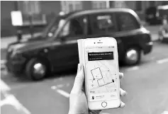  ??  ?? A woman poses holding a smartphone showing the App for ride-sharing cab service Uber in London. Uber is expected to tell a British employment appeal tribunal that its drivers are self-employed and not workers entitled to a range of extra benefits, less...