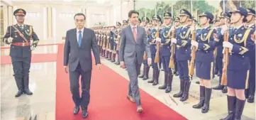  ??  ?? Trudeau and Li walk past Chinese paramilita­ry guards during a welcome ceremony at the Great Hall of the People in Beijing. — AFP phoro