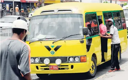  ??  ?? A bus conductor in Half-Way Tree, St Andrew gets passengers to enter his vehicle.