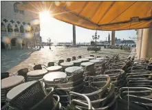  ?? [ANDREW MEDICHINI/ASSOCIATED PRESS FILE PHOTO] ?? Chairs and tables are piled in front of a bar, April 6, in St. Mark's Square, in Venice during a lockdown to prevent the spread of the coronaviru­s.