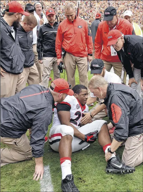  ?? BRANT SANDERLIN / BSANDERLIN@AJC.COM ?? Bulldogs coach Mark Richt and his staff look on with deep concern as trainers attend to star running back Nick Chubb after he suffered a gruesome knee injury on the first play from scrimmage Saturday in Knoxville.