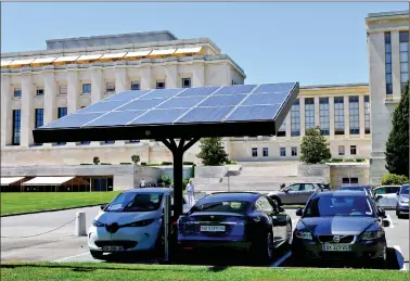  ?? REUTERS ?? Solar panels are pictured over an electric car charging station, where a Tesla and a Renault are parked, at the United Nations in Geneva, Switzerlan­d on Friday.