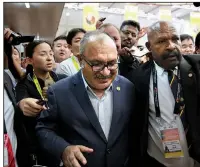  ?? AP/AARON FAVILA ?? Papua New Guinea Prime Minister Peter O’Neill is escorted by security Sunday as he is chased by reporters after reading a statement at the end of the APEC 2018 summit at Port Moresby, Papua New Guinea.