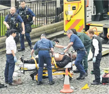  ??  ?? Paramedics attend alleged attacker Khalid Masood outside the Palace of Westminste­r after the stabbing of Pc Keith Palmer