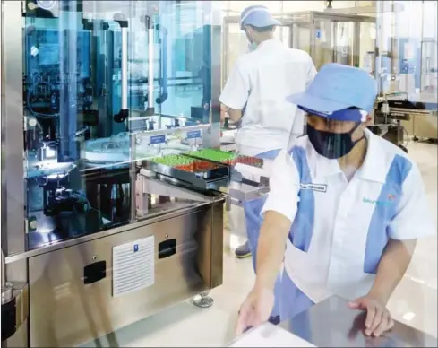  ?? AFP ?? Employees work on the production line of Covid-19 coronaviru­s vaccines at the Bio Farma Pharmacy, which will produce the vaccine early next year with a production capacity of 250 million vaccines a year, in Bandung, West Java, Indonesia.