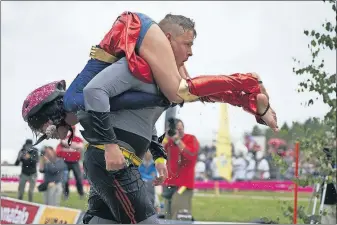  ?? [DAVID KEYTON/THE ASSOCIATED PRESS] ?? Men find all kinds of ways to carry women as they take part in the 278-yard obstacle course for the world championsh­ip wife-carrying race in Finland.