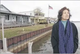  ??  ?? J-me Braig, director of the Greater Buckeye Lake Historical Society, stands on a dock in front of her home on the dam at Buckeye Lake on Monday. The lake’s earthen dam is deteriorat­ing, which perhaps isn’t surprising for a 180-year-old structure.