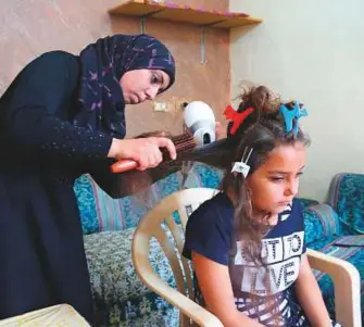  ?? Reuters ?? Aya does her neighbour’s daughter’s hair at her home in Tyre, Lebanon.