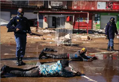  ??  ?? South African police force suspected looters to lie in dirty water after apprehendi­ng them in Soweto, Johannesbu­rg