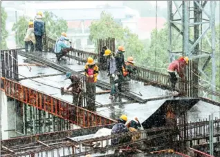  ?? SUN RETHY KUN/AFP ?? Cambodian labourers work under the rain on a high-rise building constructi­on site in Sihanoukvi­lle. Thousands of Cambodians pushed by poverty seek to cash in on the once sleepy seaside town’s Chinese-funded constructi­on boom. But the work is mostly unregulate­d, low paid, often dangerous – and sometimes deadly.