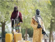  ??  ?? A member of a civilian vigilante group holds a hunting rifle while a woman pumps water into jerrycans in Kerawa, Cameroon, in this file photo. (Reuters)