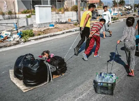  ?? Petros Giannakour­is / Associated Press ?? A child sits between plastic bags Thursday as migrants pull their belongings in Kara Tepe, near Mytilene, the capital of the northeaste­rn island of Lesbos, Greece. Police are moving hundreds of migrants to an army-built camp on the island.