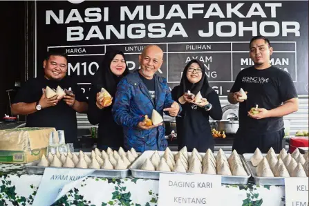  ??  ?? Tasty and affordable: Faidzal (centre) and his workers holding packets of ‘nasi muafakat’ at Ejohng Concept Restaurant in Taman Sri Piulai Perdana, Johor Baru.