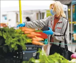  ?? NELVIN C. CEPEDA U-T FILE ?? Gail Donahue points to the fresh vegetables she wanted at the farmers market in Little Italy in April 2020. Mask mandates were lifted in California a year ago.